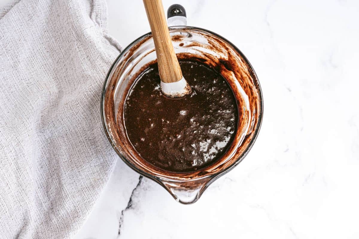 Glass liquid measuring cup with homemade brownie batter and rubber spatula.