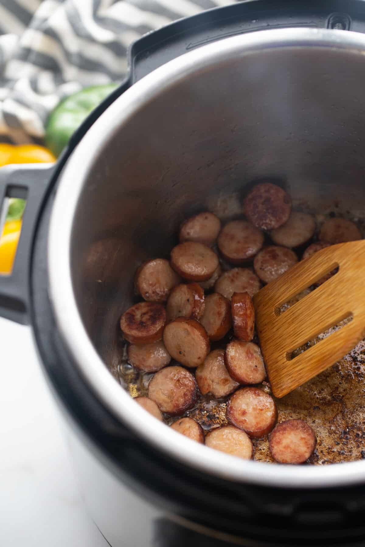 Sliced andouille chicken sausage cooking in an instant pot on saute.