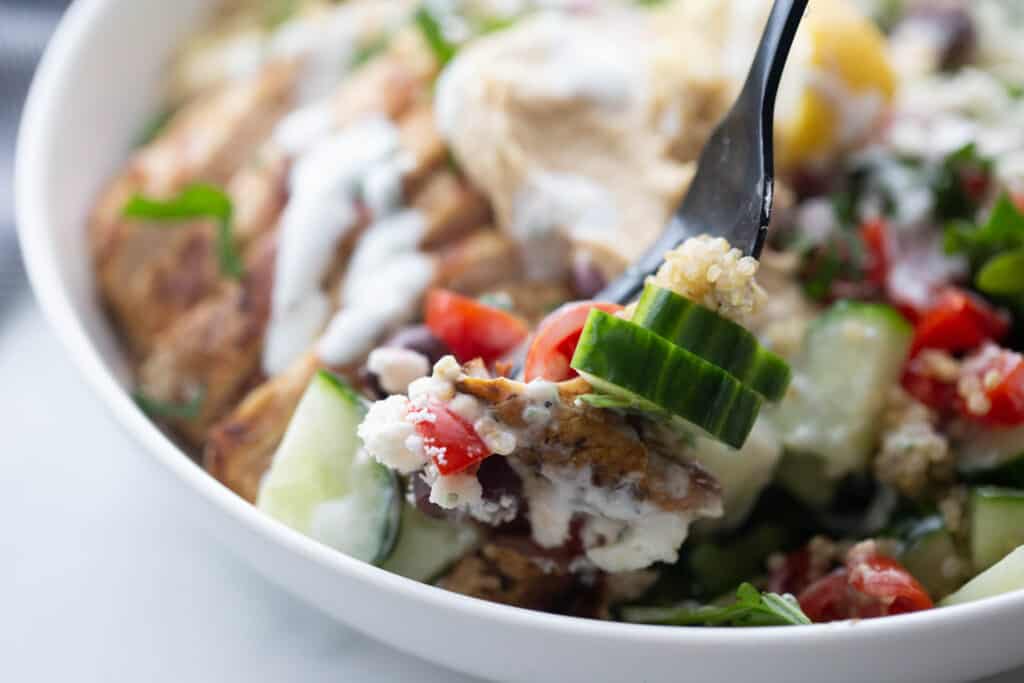 Close up of a fork taking a bite of a Chicken Mediterranean Bowl.