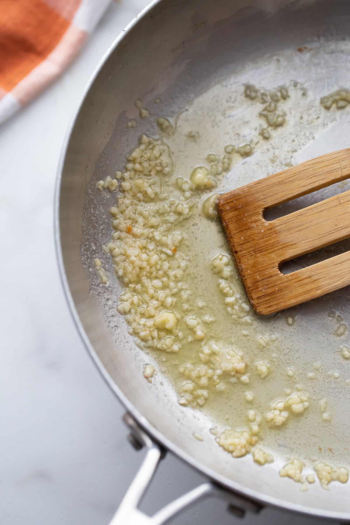 Garlic and olive oil in a stainless steel pan.