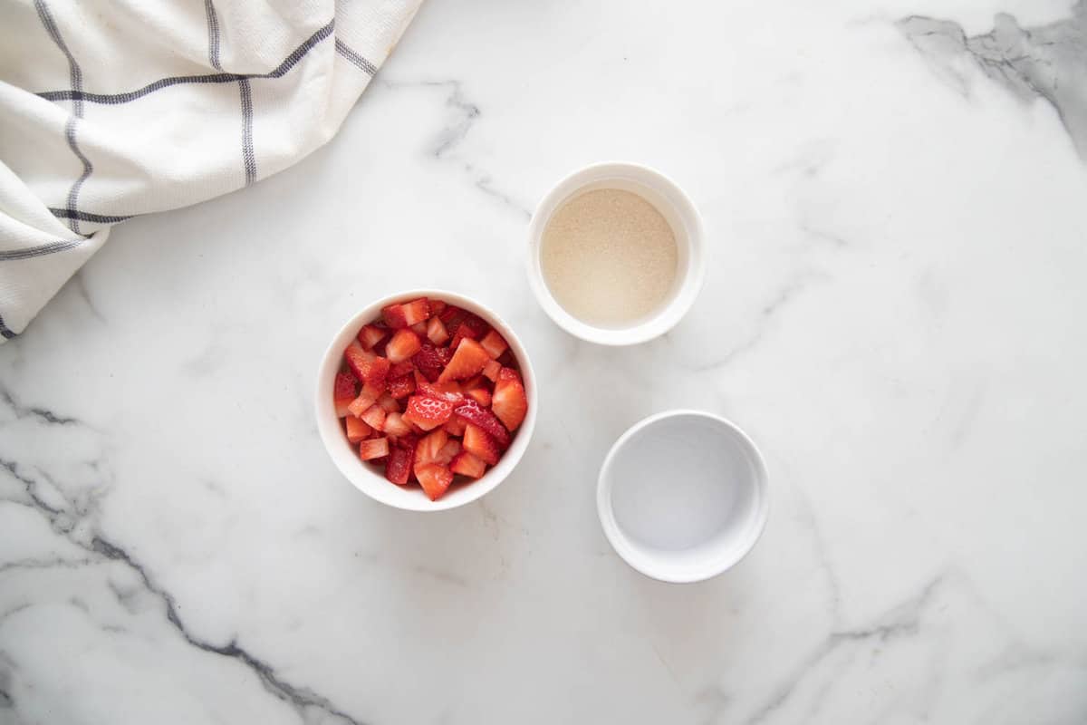 Overhead photo of ingredients for healthy mini cheesecakes strawberry topping on a white countertop.