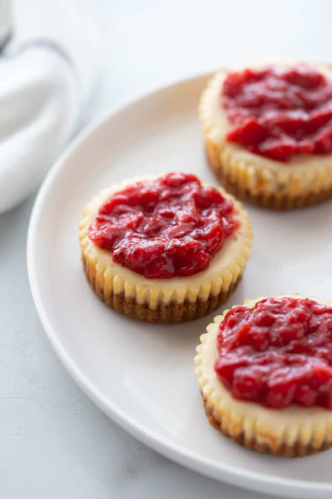 Mini cheesecakes with strawberry topping on a white plate