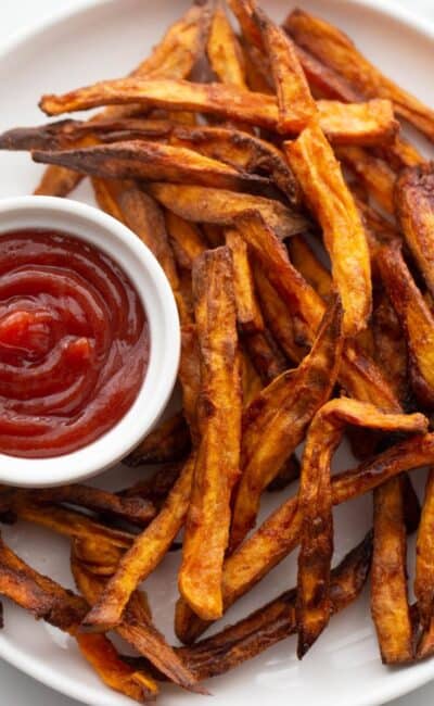 Plate of crispy golden brown air fryer french fries served with ketchup.