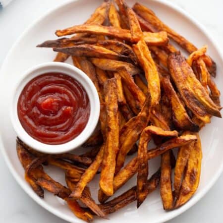 Plate of crispy golden brown air fryer french fries served with ketchup.
