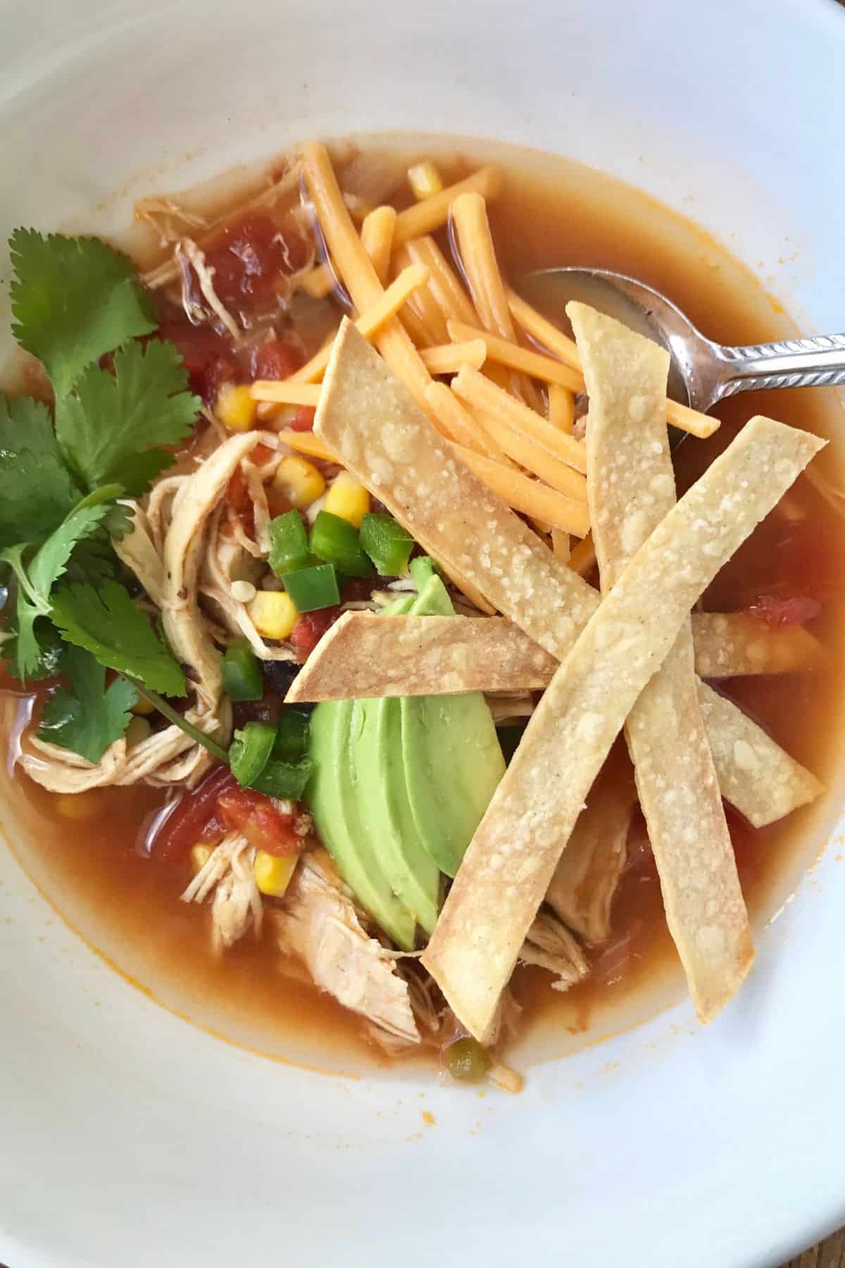 Bowl of Instant Pot Chicken tortilla soup with all the toppings.