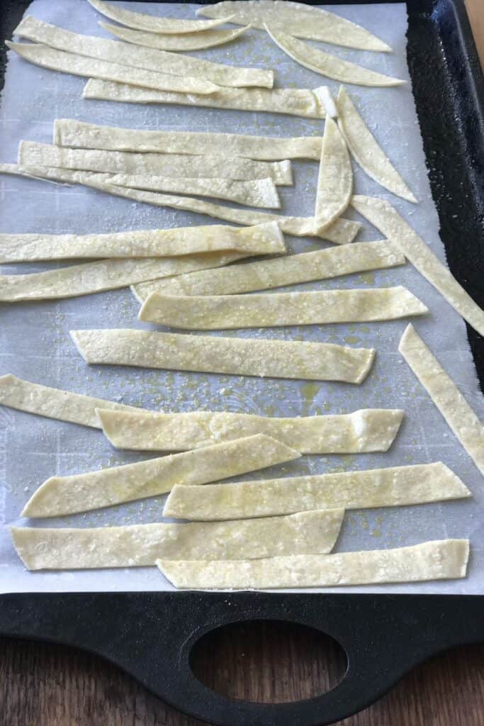 Corn tortillas cut into strips on a sheet pan.