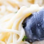 Pinterest image for Healthier Alfredo Sauce with a close up photo of pasta and sauce.