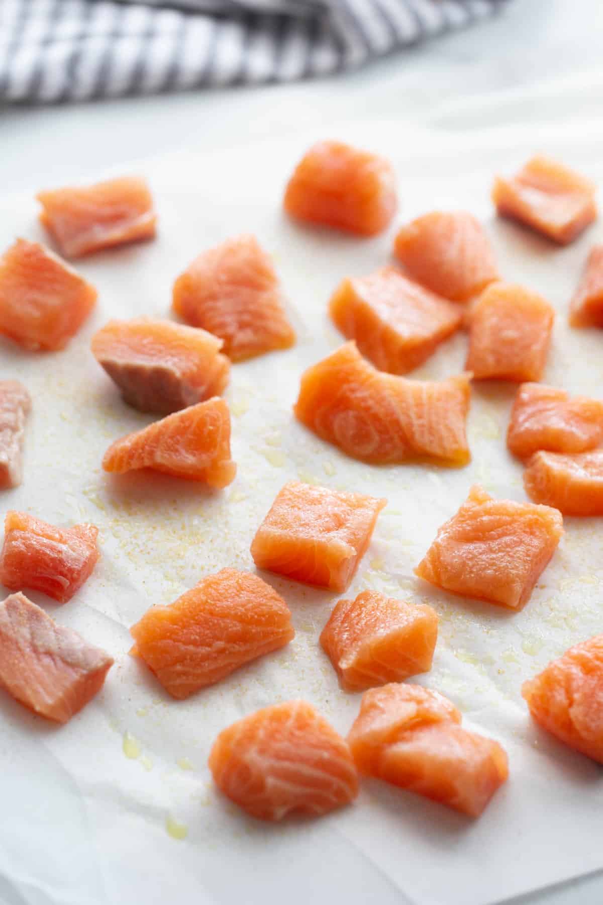 Cubes of seasoned salmon chunks on parchment paper.