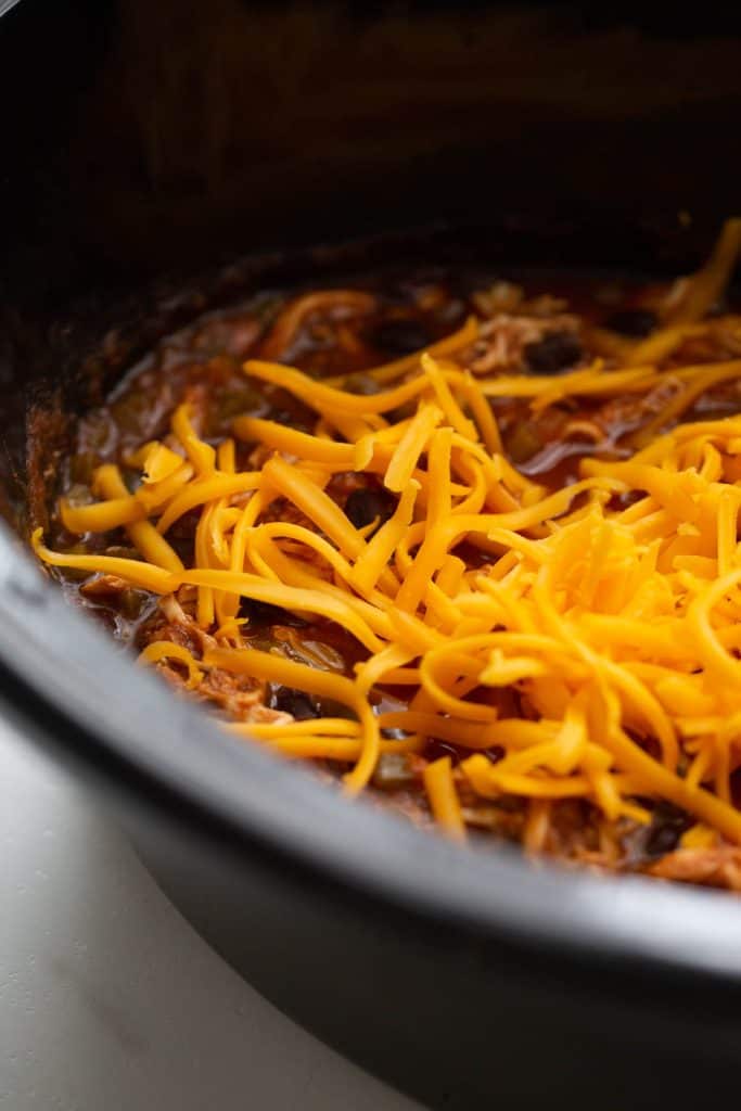 Shredded cheese on top of a slow cooker enchilada casserole.