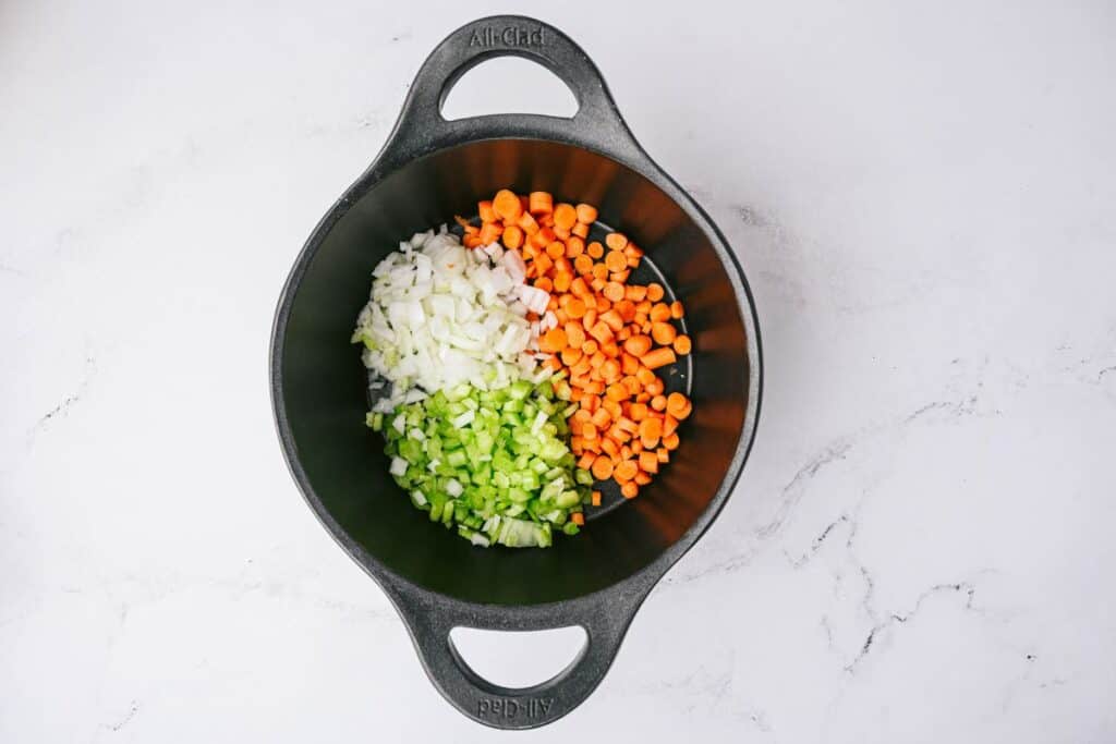Celery, onions, and carrots in a large cast iron pan.