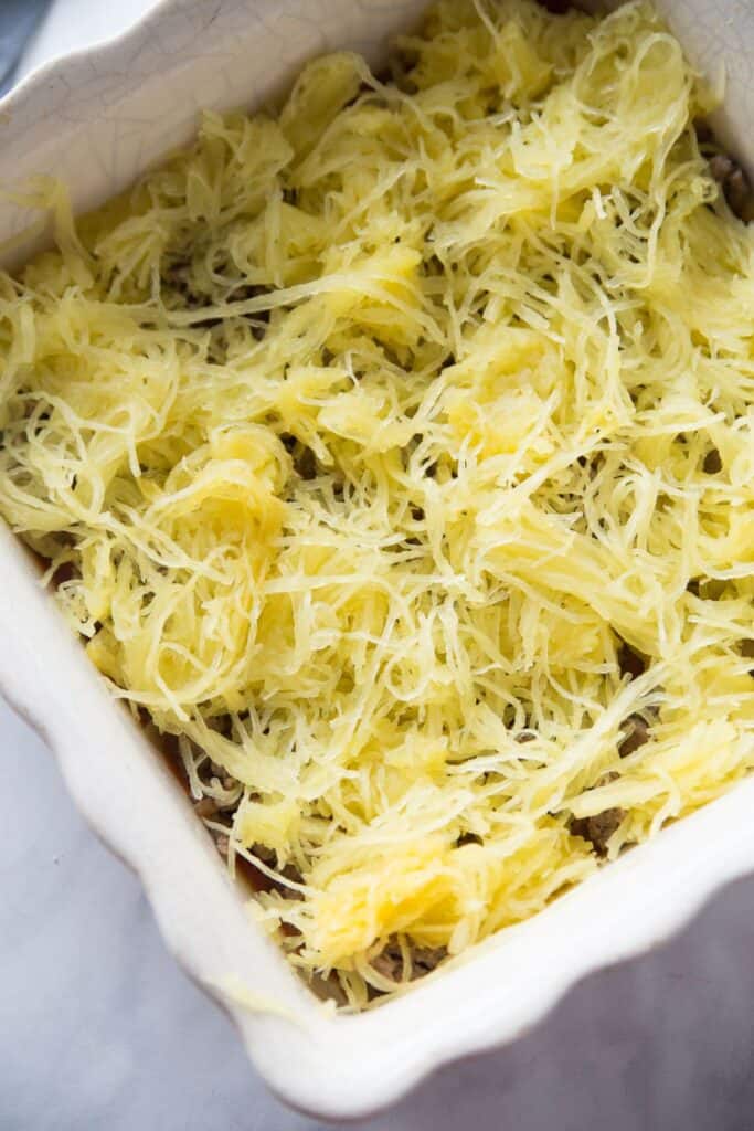 Baking dish layered with spaghetti squash, sauce, cheese, and meat.