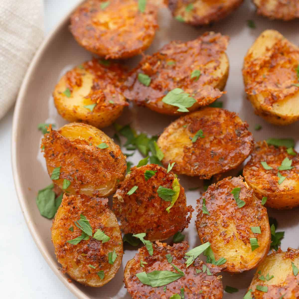 Crispy oven roasted baby potatoes with parmesan cheese and fresh parsley as garnish.