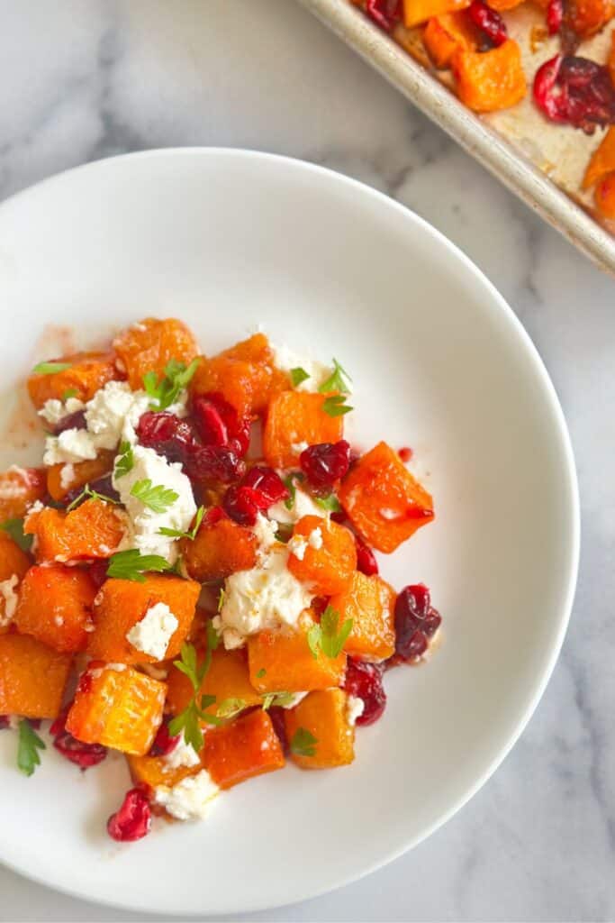 Plate of honey cinnamon roasted butternut squash with cranberries and goat cheese.
