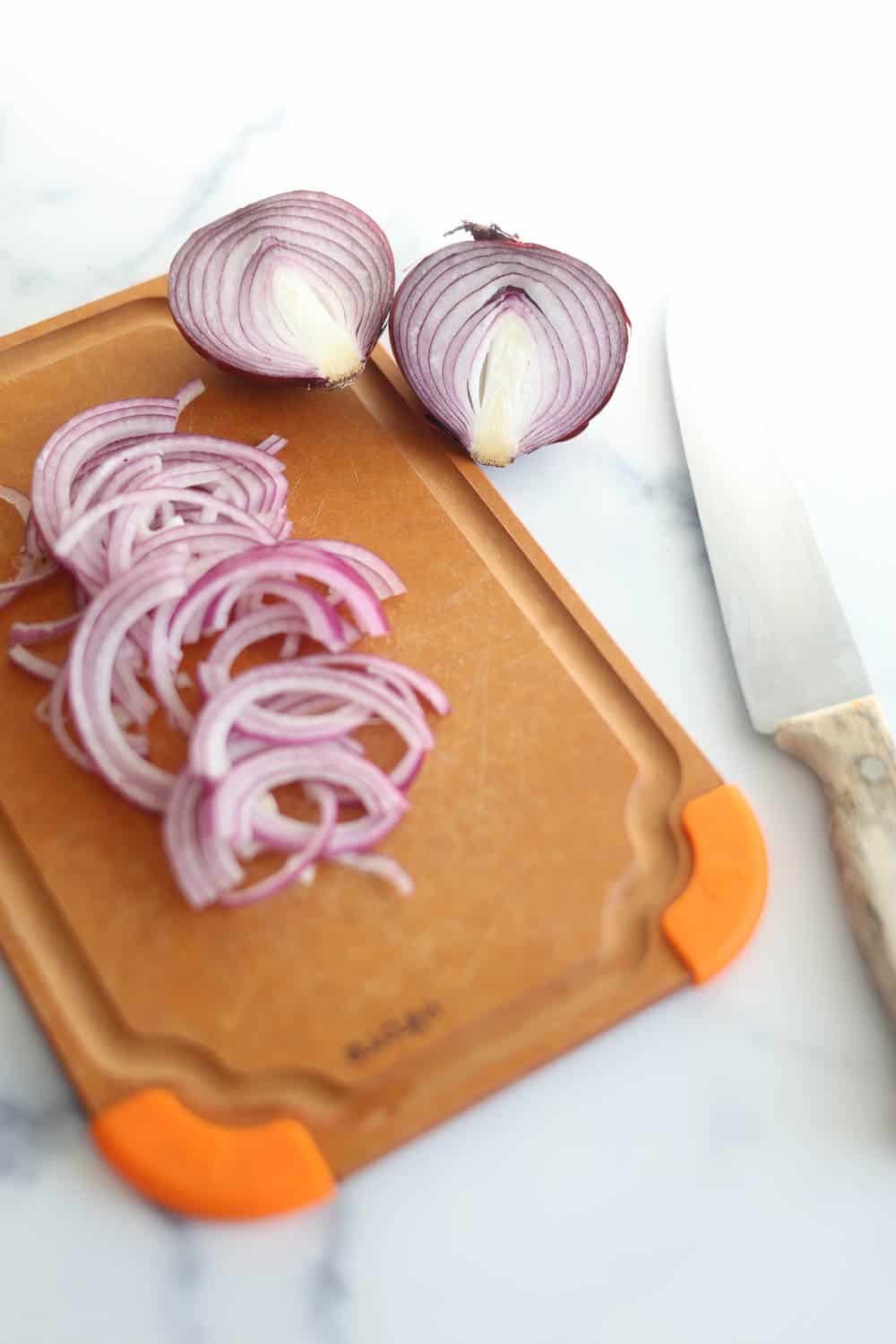 Thinly sliced red onions on a cutting board.
