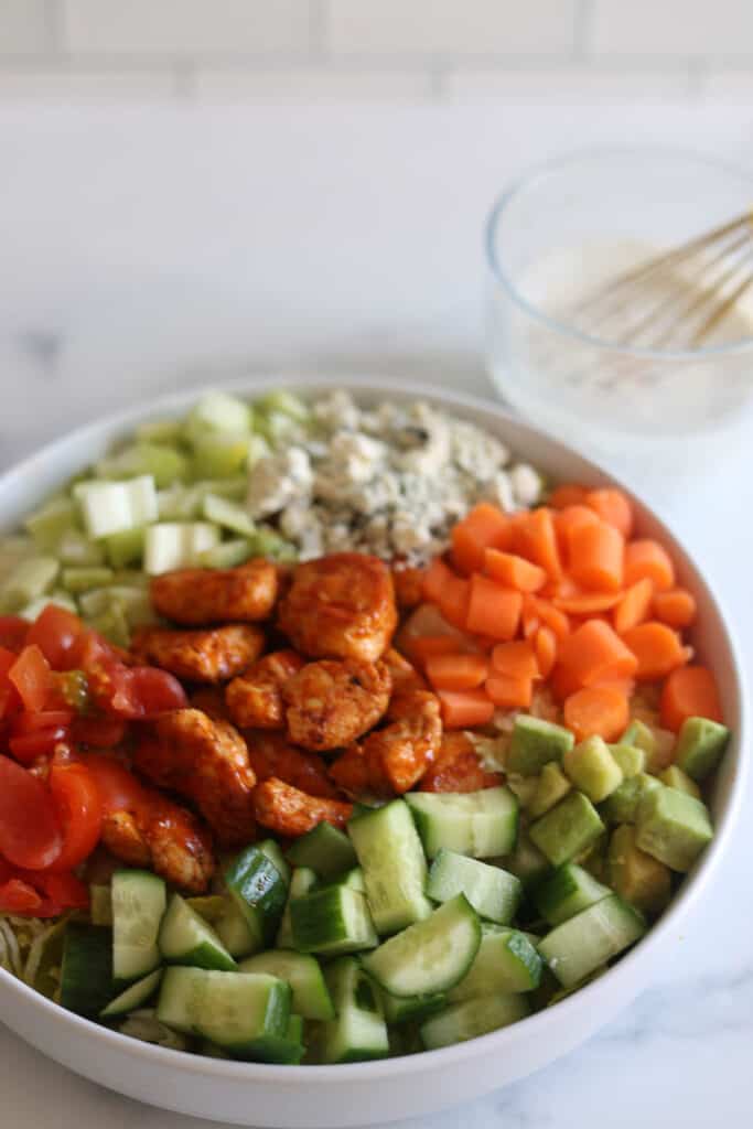 Vegetables and buffalo chicken bites in a bowl for buffalo chicken salad.