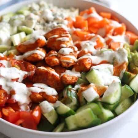 Close up photo of restaurant style buffalo chicken salad topped with a healthy greek yogurt ranch.
