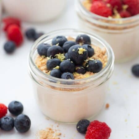 Jars of cottage cheese cheesecake snacks that are high protein and topped with fruit and graham crackers.