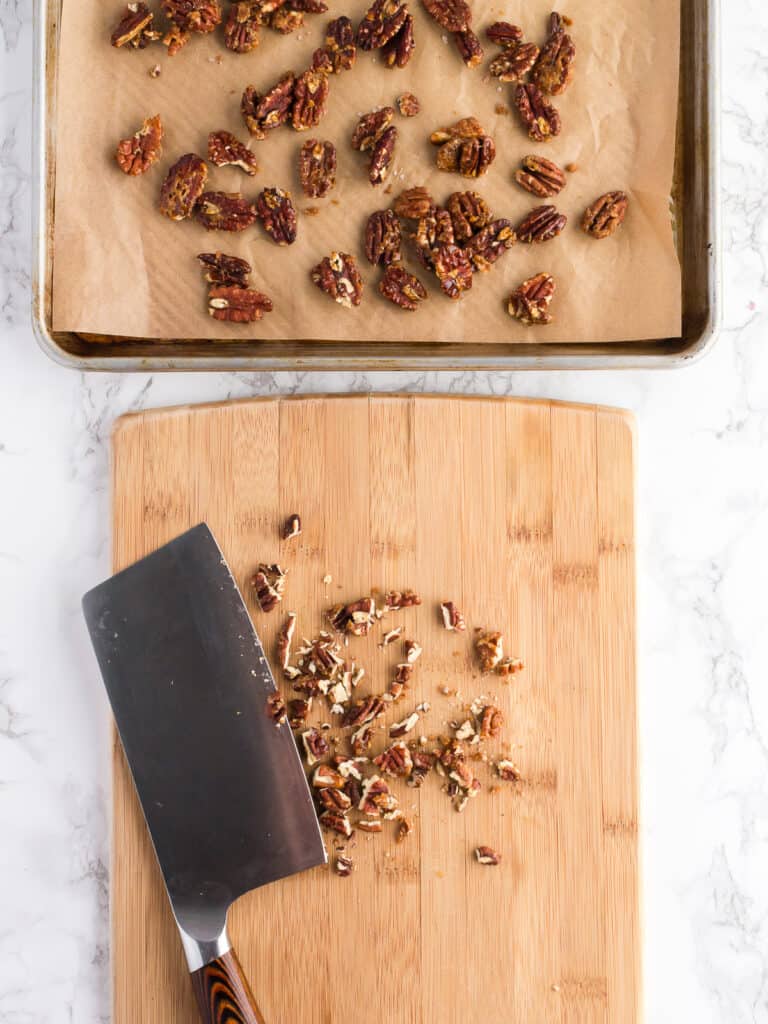 Chopped homemade candied pecans on a wooden cutting board.