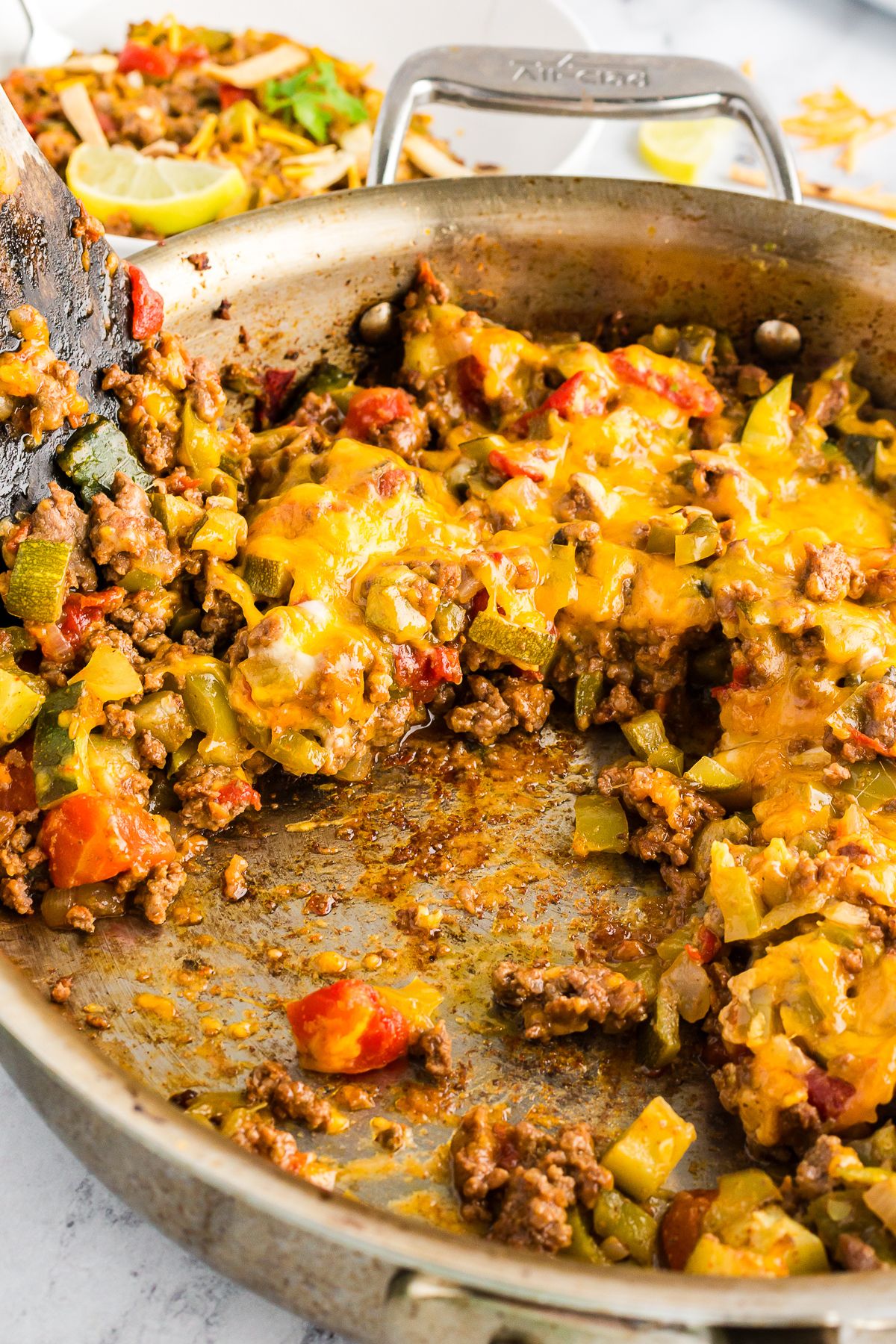 Partially eaten taco zucchini skillet in a pan, showing browned bits of meat and vegetables with a spatula partially visible.