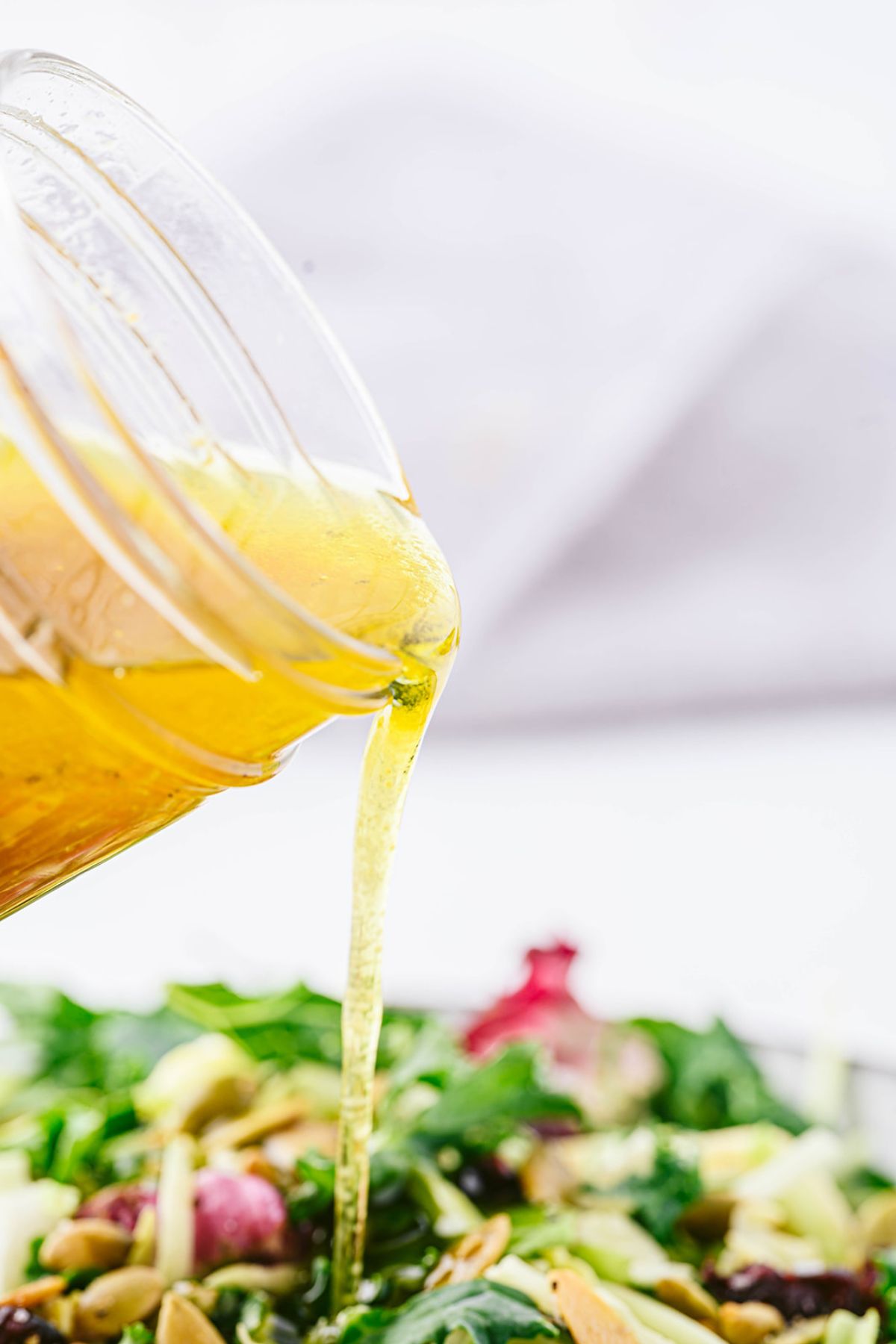 Close-up of apple cider vinaigrette being poured over a fall salad.