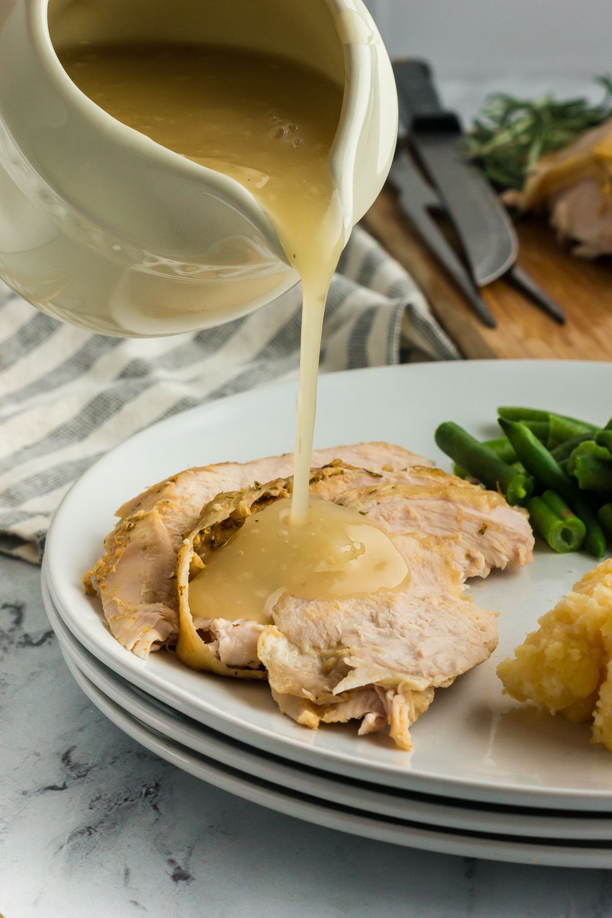 Graving being poured onto a plate of slow cooker turkey breast.