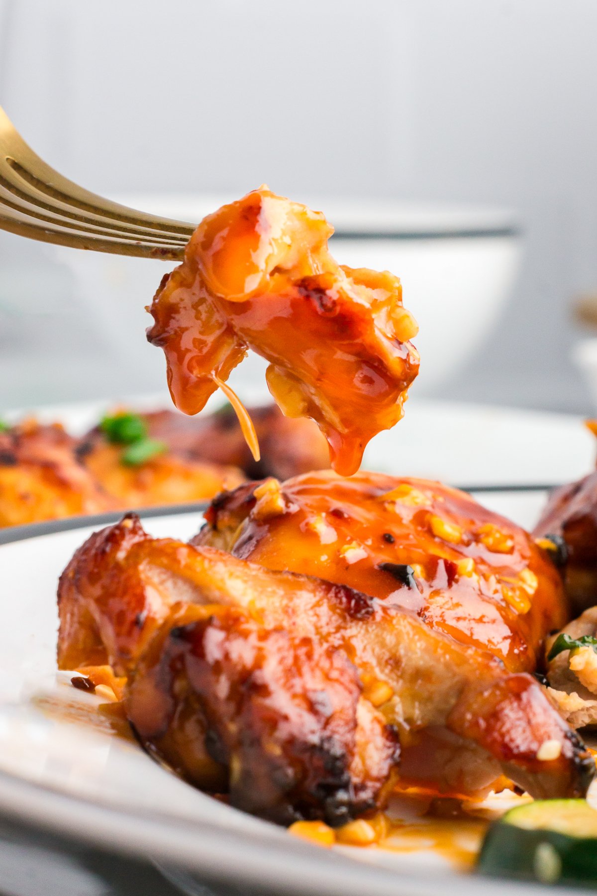 a bite of chicken cut off of a chicken thigh coated in sticky glaze