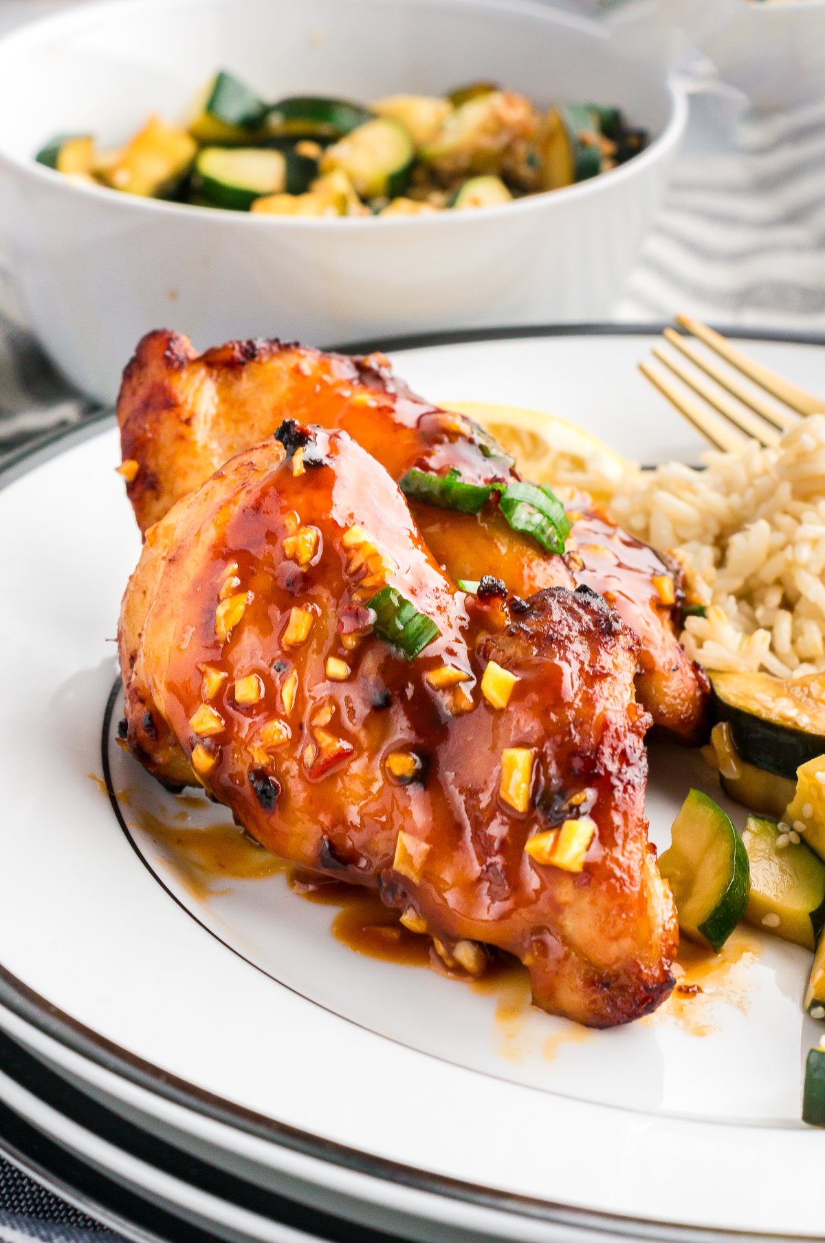 A plate with juicy air fryer chicken thigh, rice and veggies. 