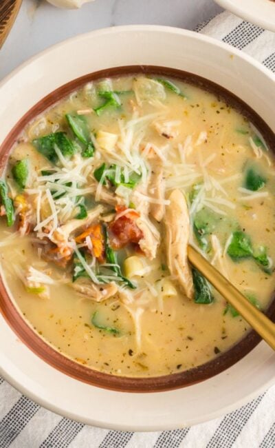 A close-up of a creamy Marry Me Chicken Soup in a white bowl, garnished with fresh basil and red pepper flakes.