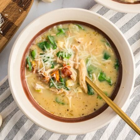 A close-up of a creamy Marry Me Chicken Soup in a white bowl, garnished with fresh basil and red pepper flakes.