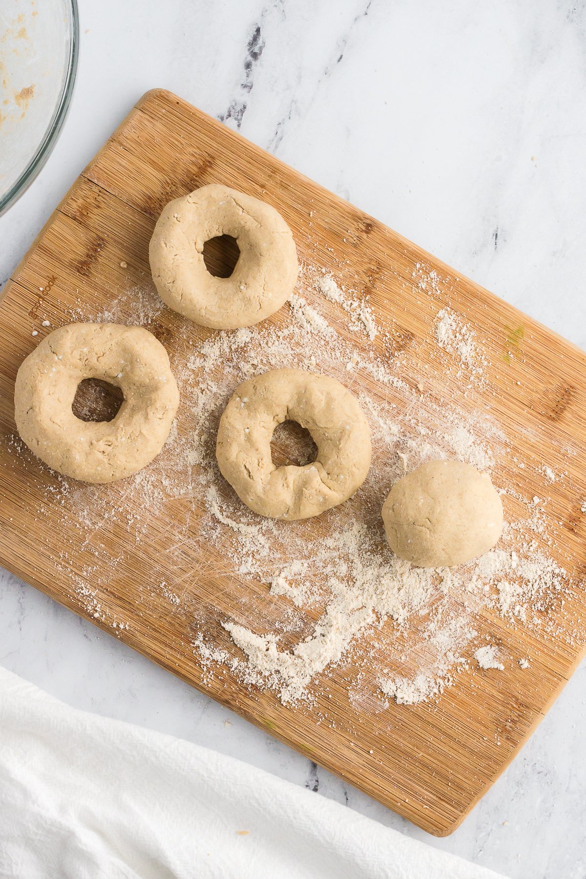 formed bagels on a cutting board before being cooked, shot from overhead