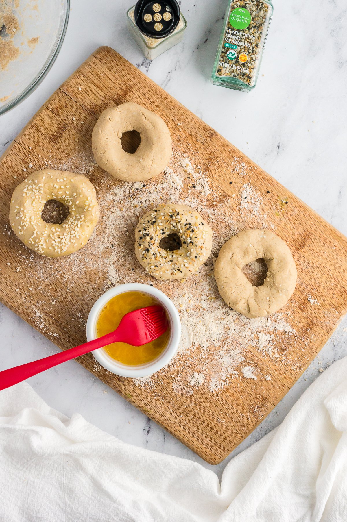 bagels before being cooked with an egg wash brushed on and toppings added, shot from overhead