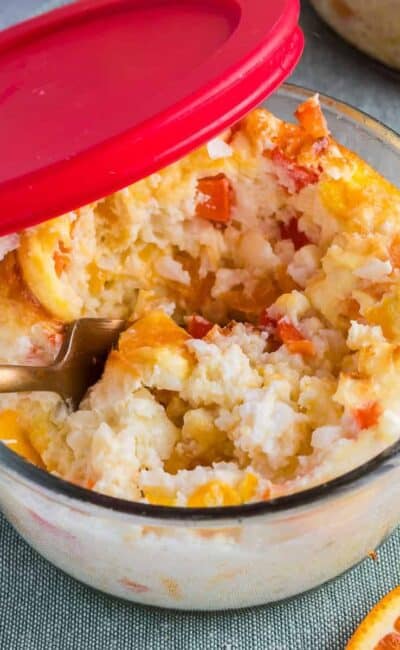 Breakfast meal prep bowls in a glass container with a red lid and a gold spoon inside.