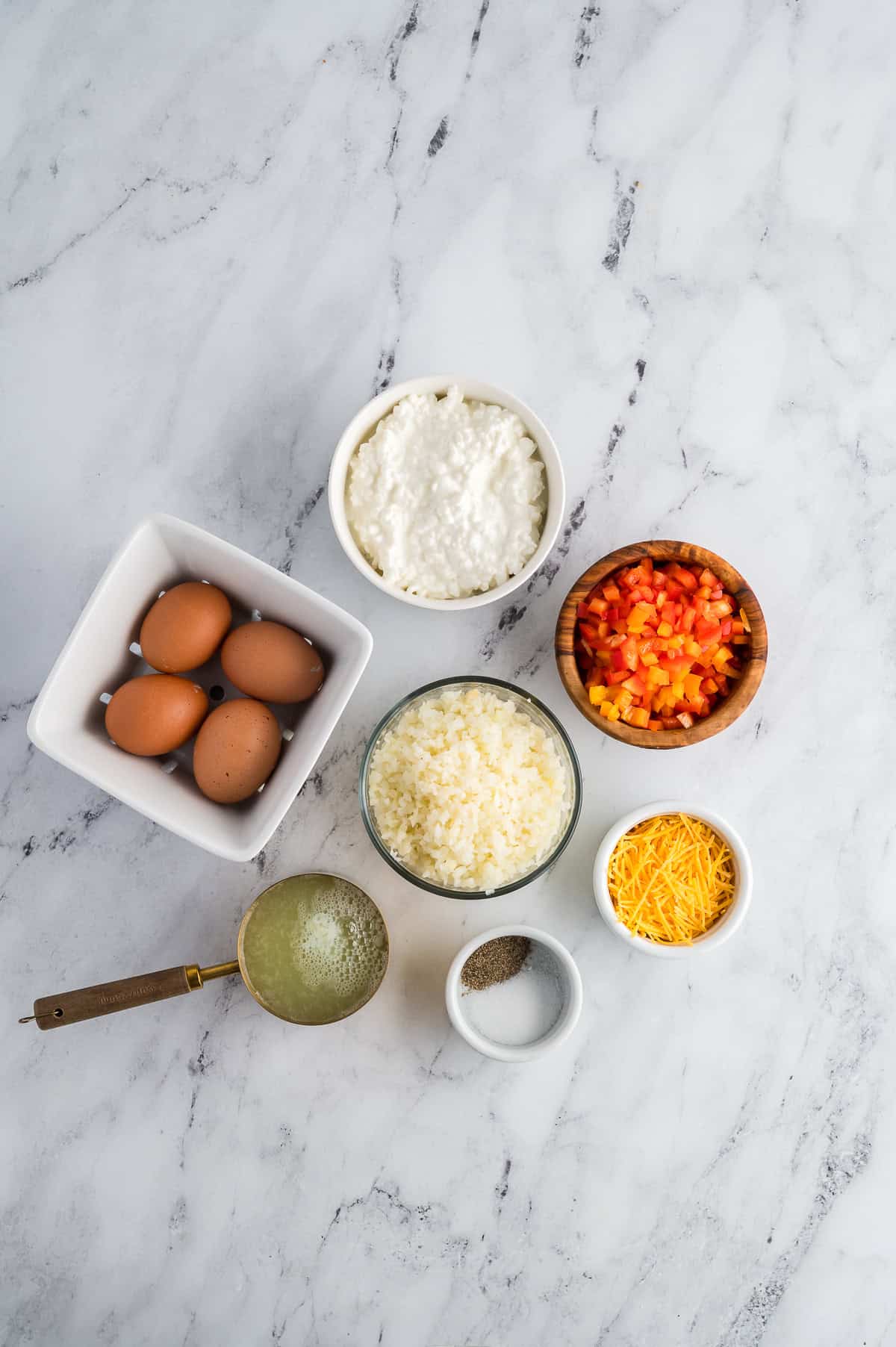 Ingredients for breakfast bowls in separate containers on a marble background.