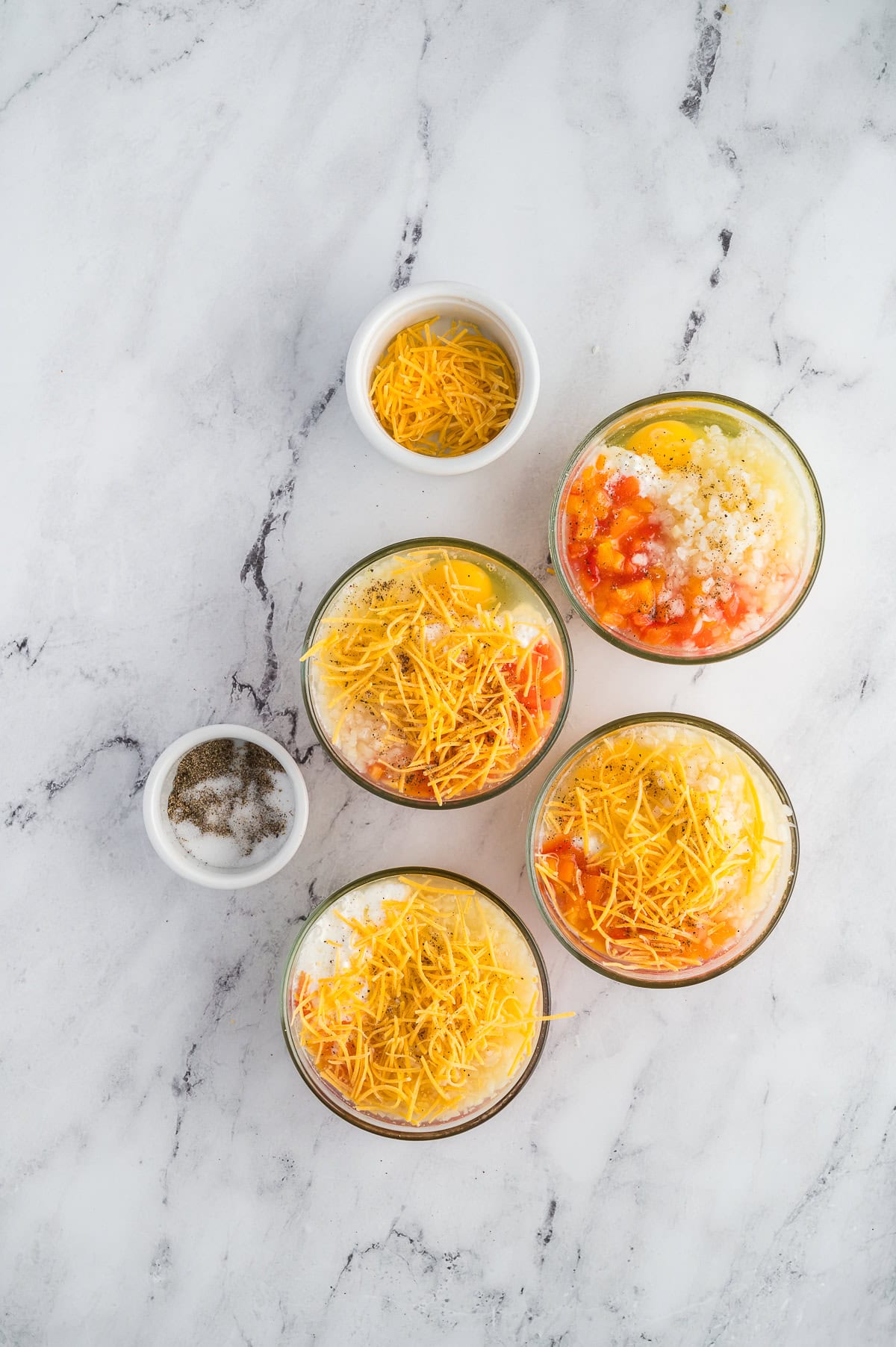 Breakfast bake ingredients in the individual cups before being cooked.
