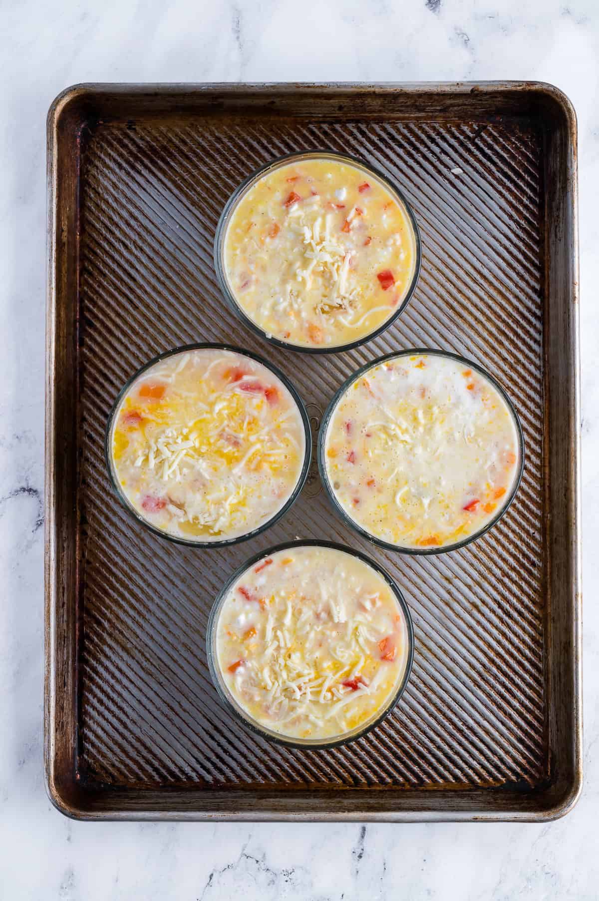 Breakfast bowls are placed on a baking sheet before being baked.