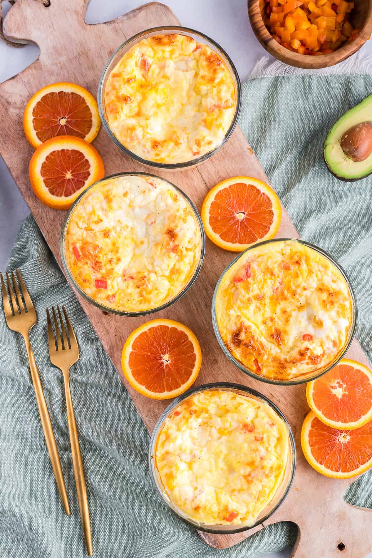 Baked breakfast bowls with citrus on a cutting board with gold forks.