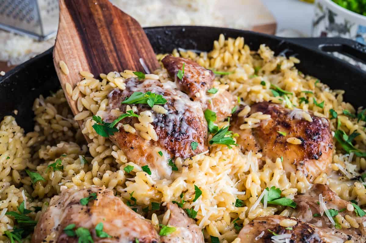 Finished one pan chicken and orzo with a wooden spoon in a skillet.