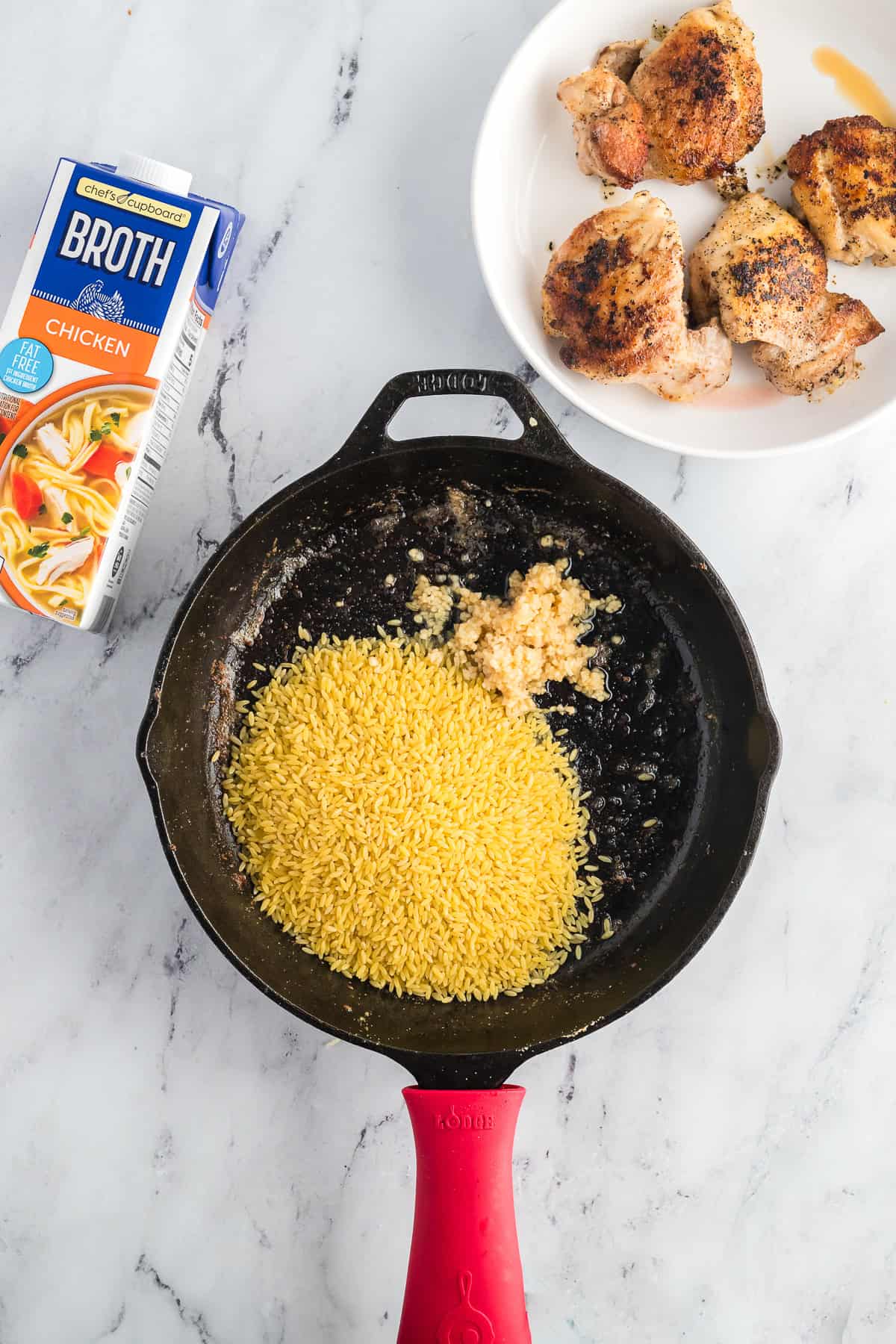 Orzo and garlic in a skillet before being browned.