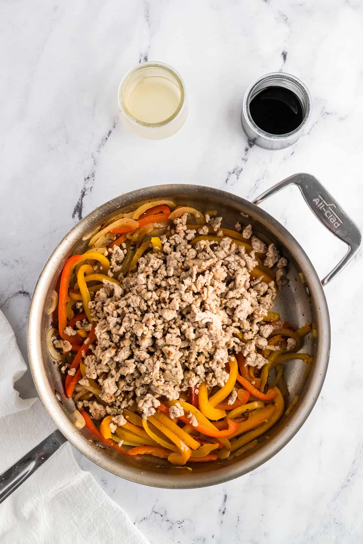 Onions, peppers, and ground chicken in a stainless steel pan.