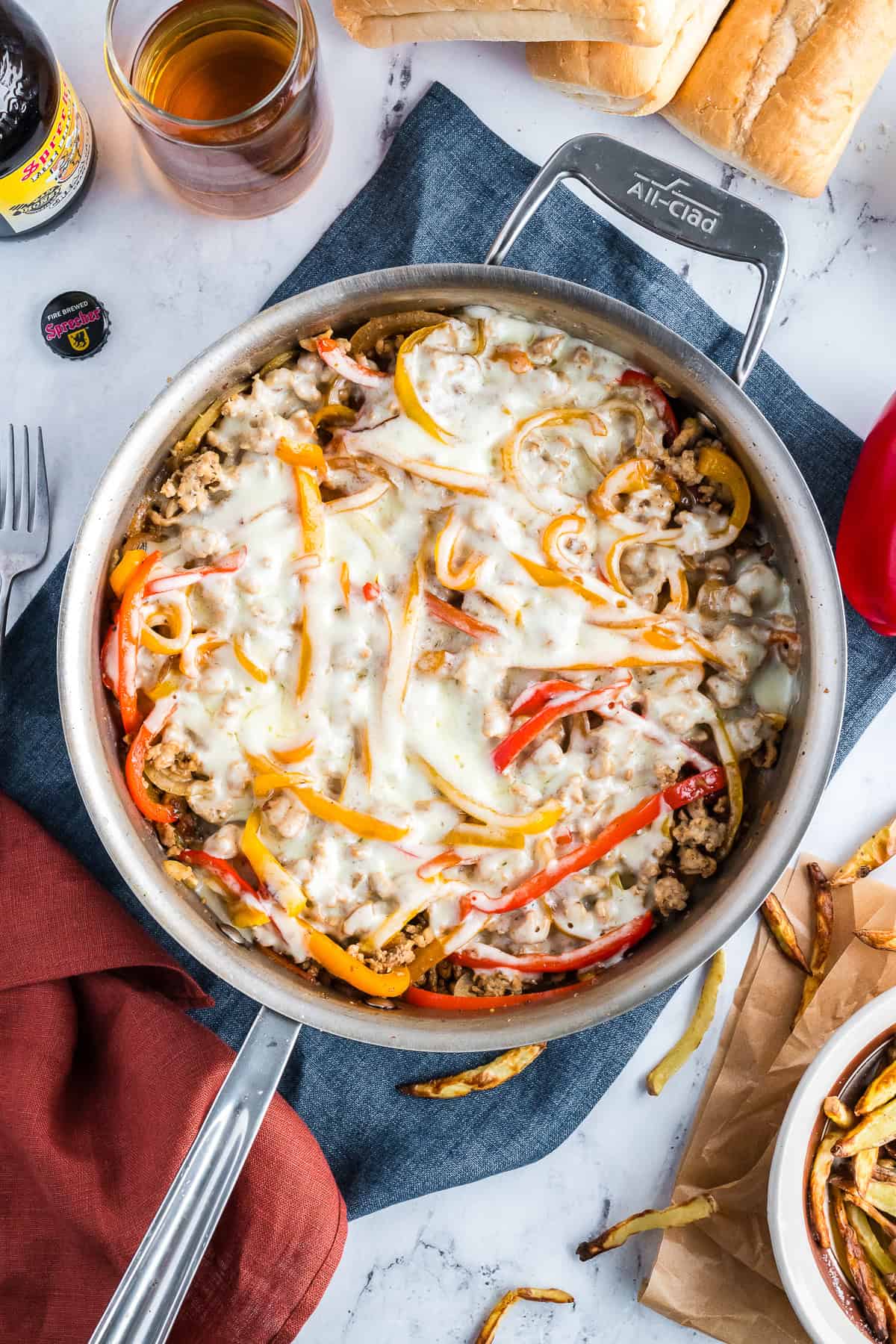 Cooked chicken cheesesteak casserole in a stainless steel pan with cheese melted on top.