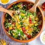 Colorful summer orzo salad with peaches, cherry tomatoes, cucumbers, and feta served in a large white bowl.