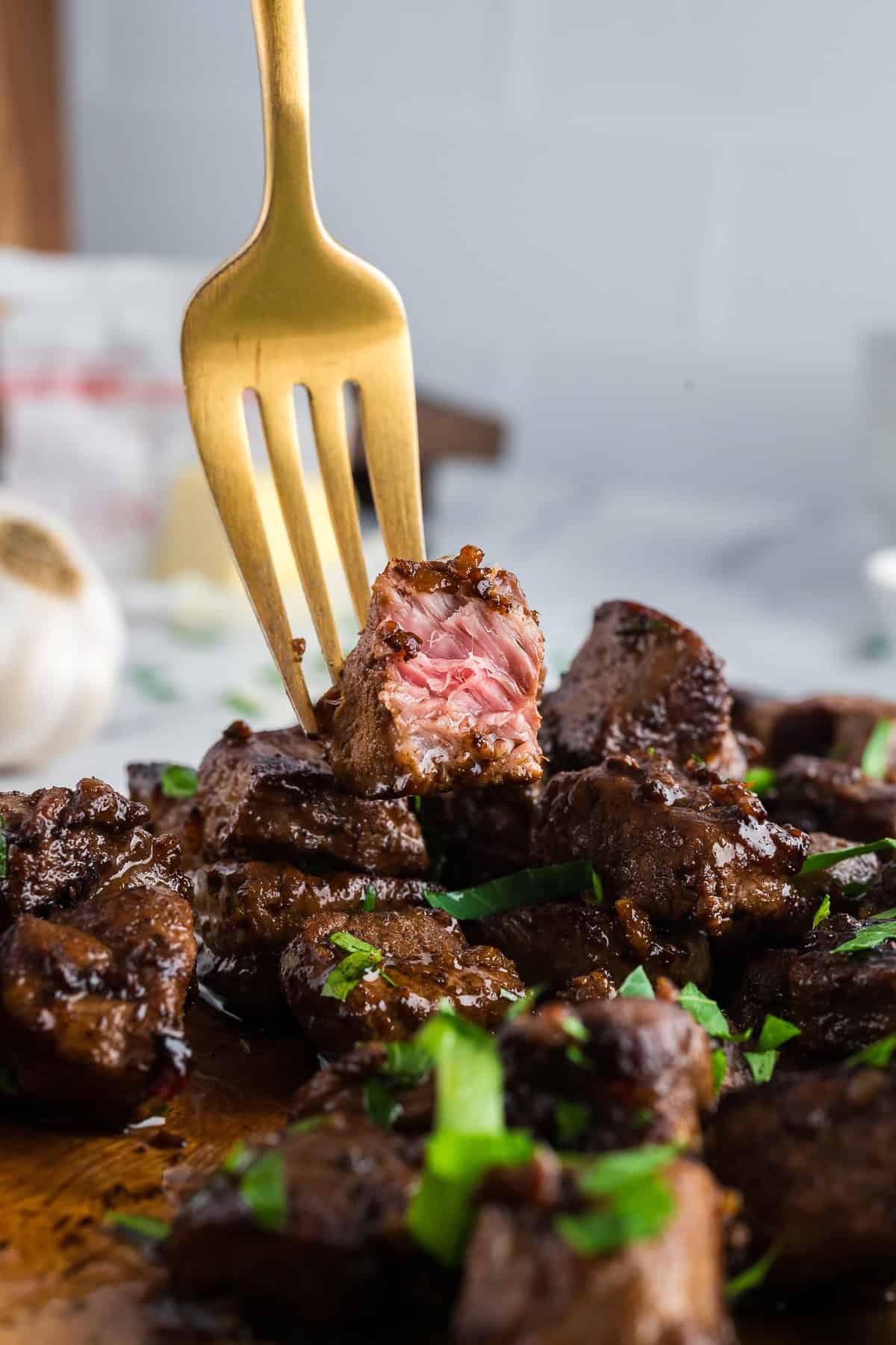 Close up of steak bites on a gold fork. 