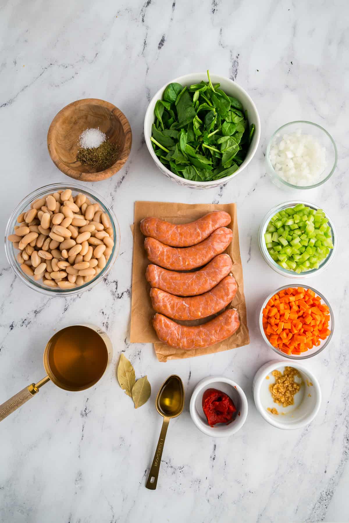 Ingredients measured and prepped for Tuscan White Bean Soup, including sausage, beans, vegetables, and broth.