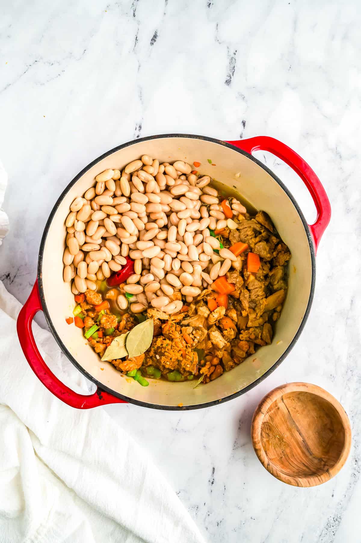 Cannellini beans and chicken broth added to the pot and stirred together.