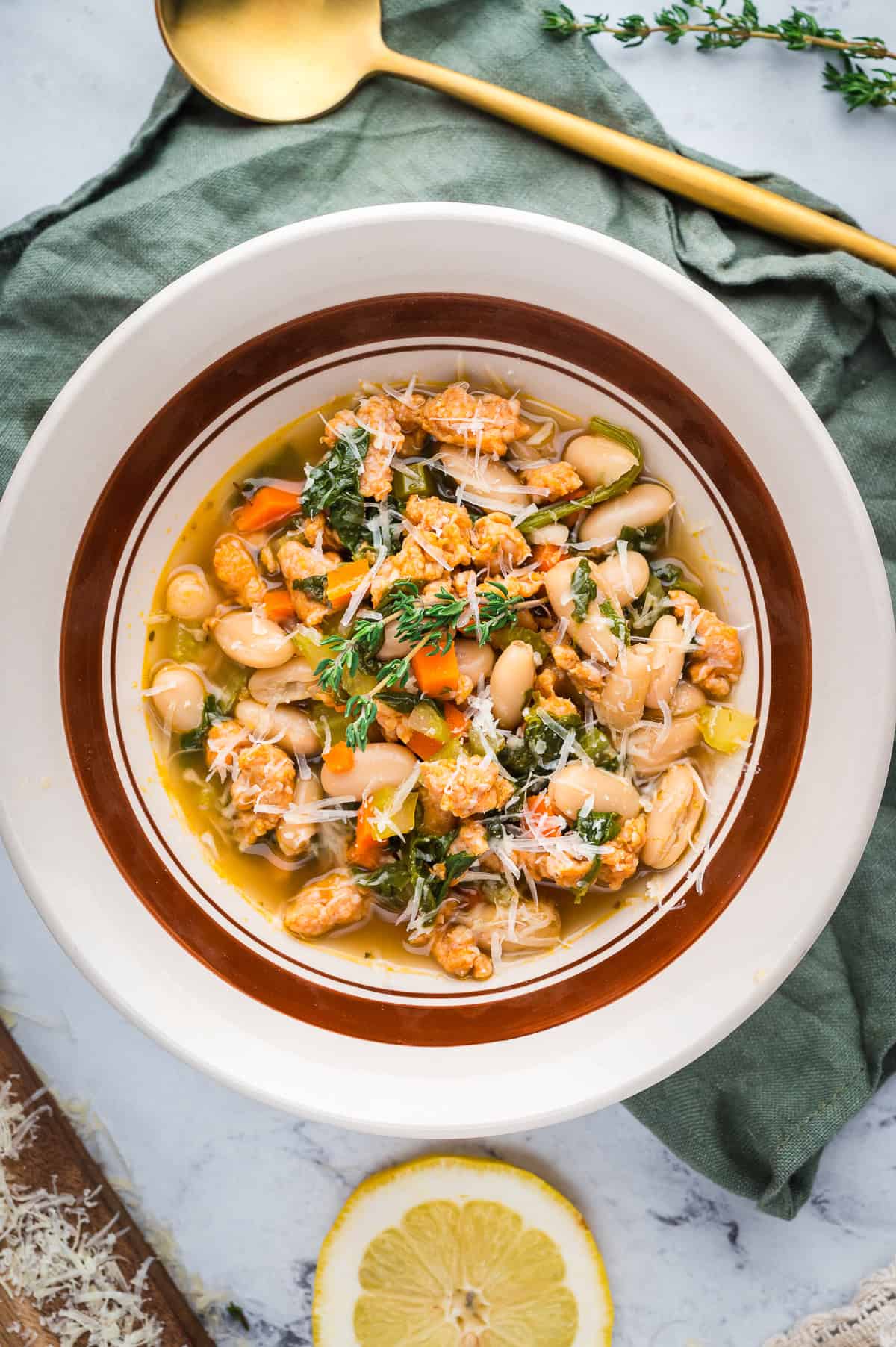 Overhead shot of hearty Tuscan White Bean Soup in a bowl, topped with grated Parmesan.