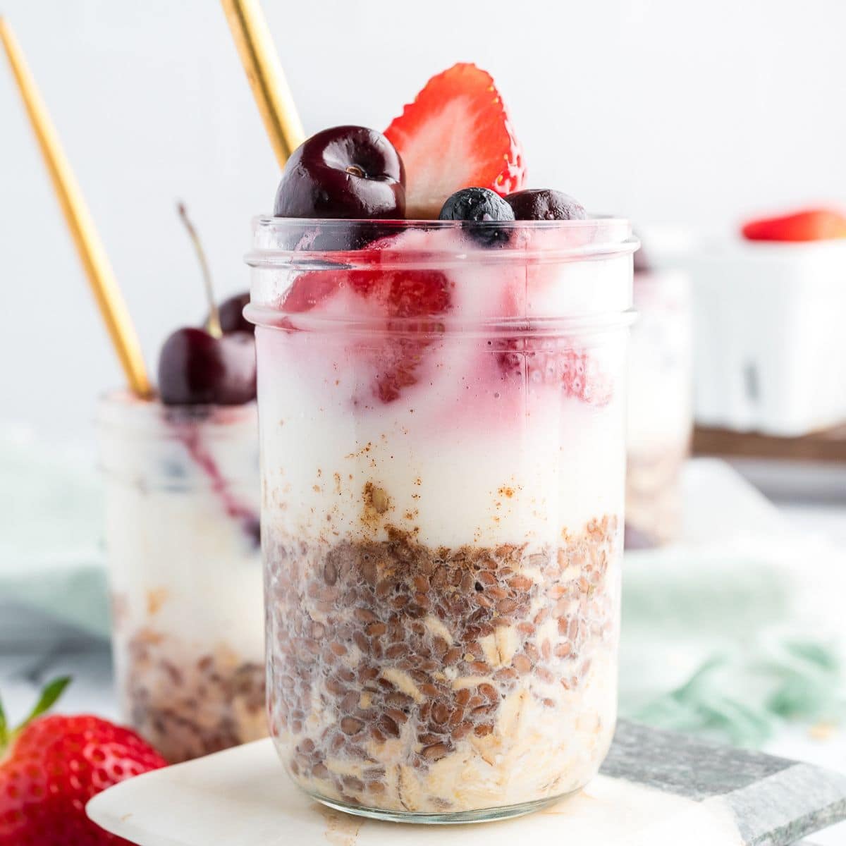 high-protein overnight oats in glass jars layered with oats, yogurt, and berries, styled with gold spoons.